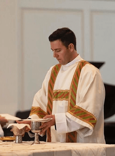 Catholic priest preparing the chalice and bread for the Eucharist during Mass