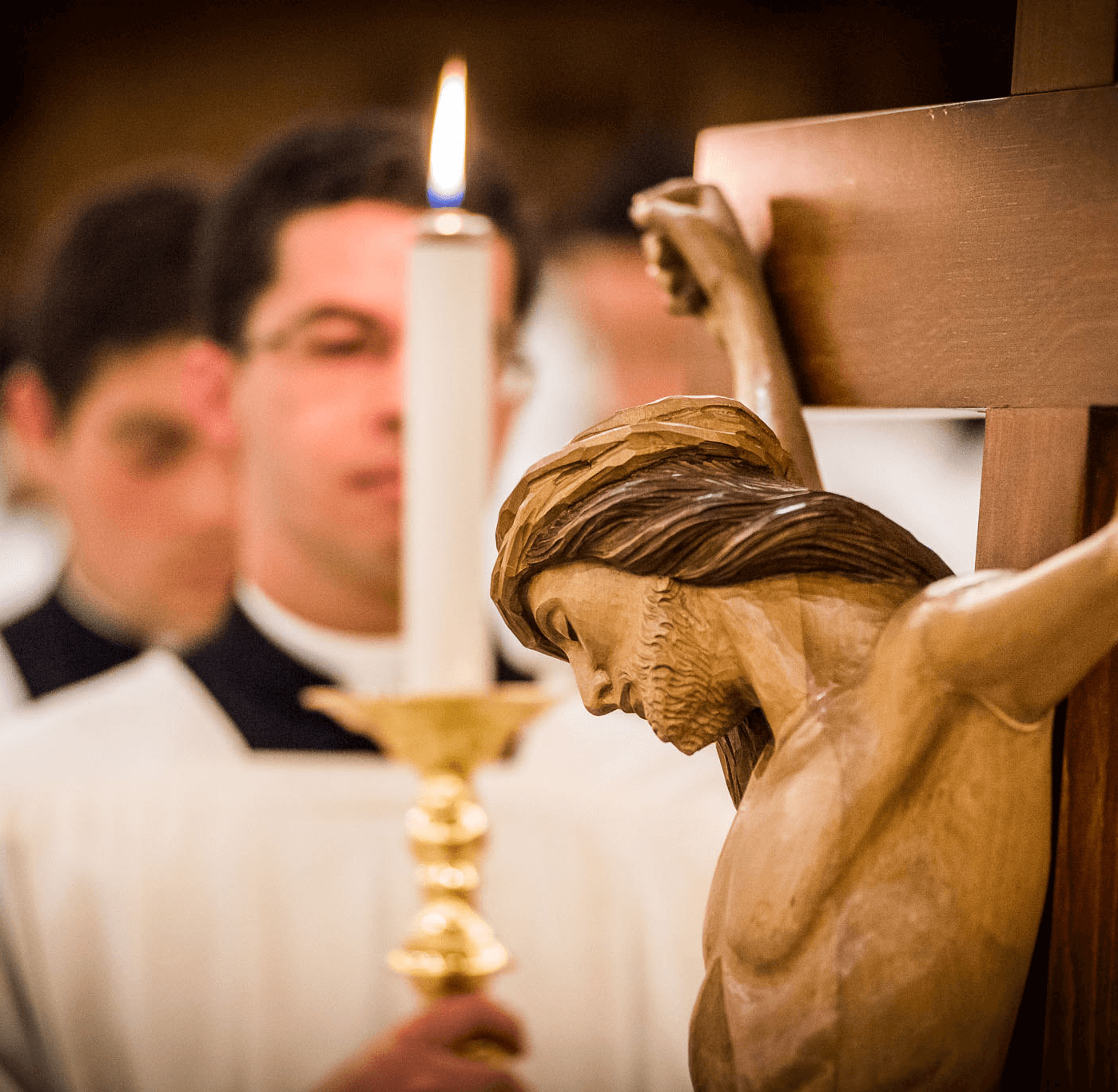Crucifix of Christ during Catholic liturgy with candle in foreground